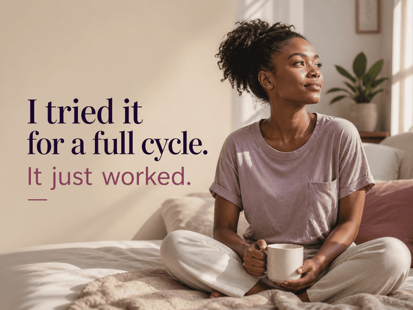 Woman sitting comfortably on a bed holding a mug in soft morning light, with the text: “I tried it for a full cycle. It just worked.” The scene conveys comfort, confidence, and wellness in a calm home setting.